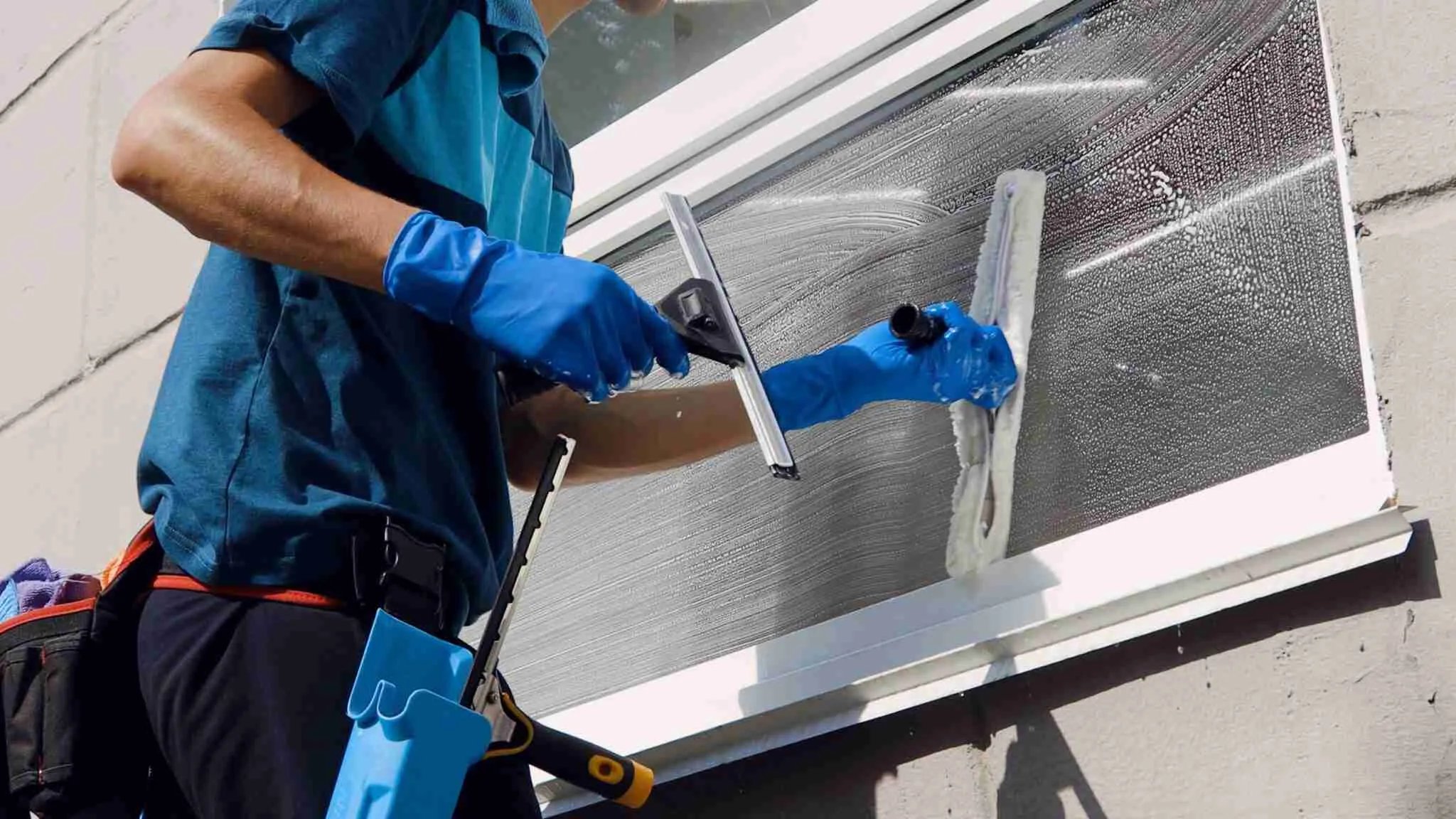 Cleaner washing a window with a squeegee